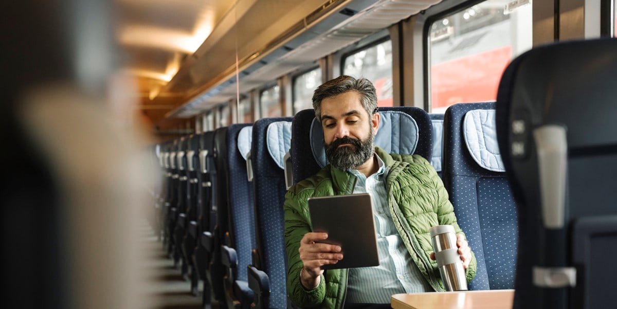 man travelling by train, using tablet